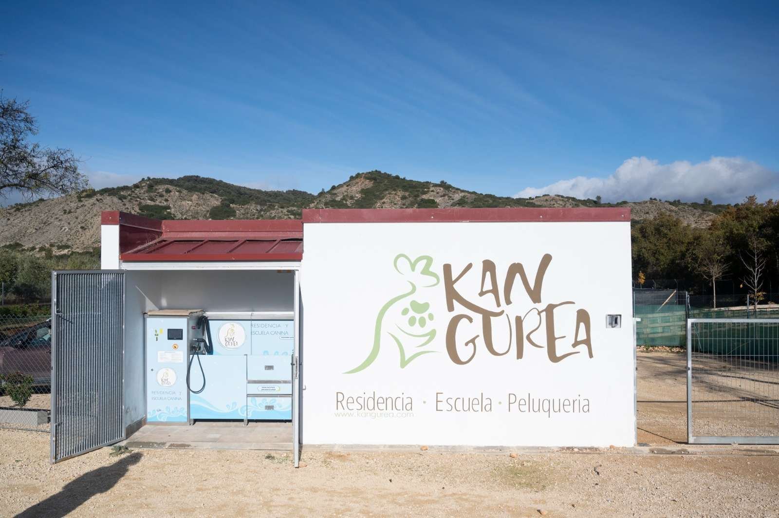 Fachada de Kan-gurea con el mural pintado a mano y la cabina de la máquina de lavado autoservicio abierta.